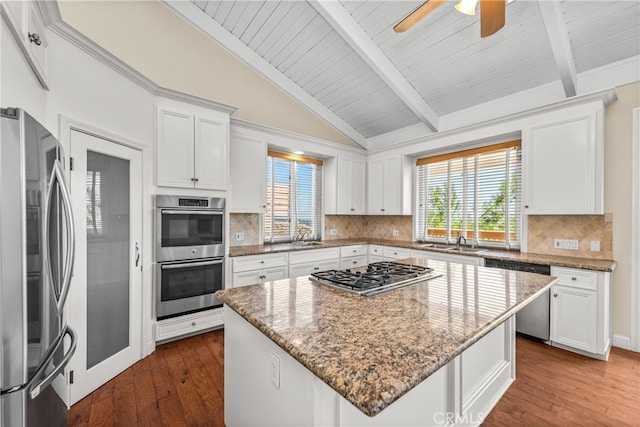 kitchen with appliances with stainless steel finishes, lofted ceiling with beams, a center island, white cabinets, and dark hardwood / wood-style floors