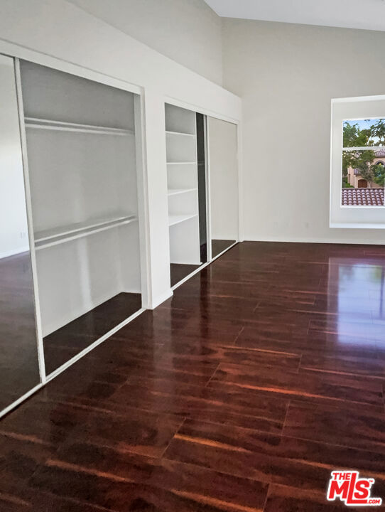 unfurnished bedroom with multiple closets and dark hardwood / wood-style floors