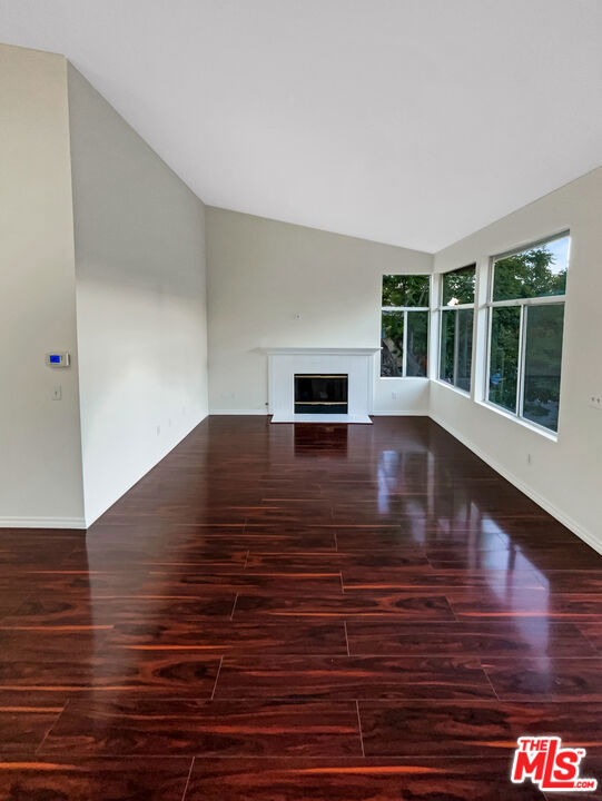 unfurnished living room with lofted ceiling and dark hardwood / wood-style flooring