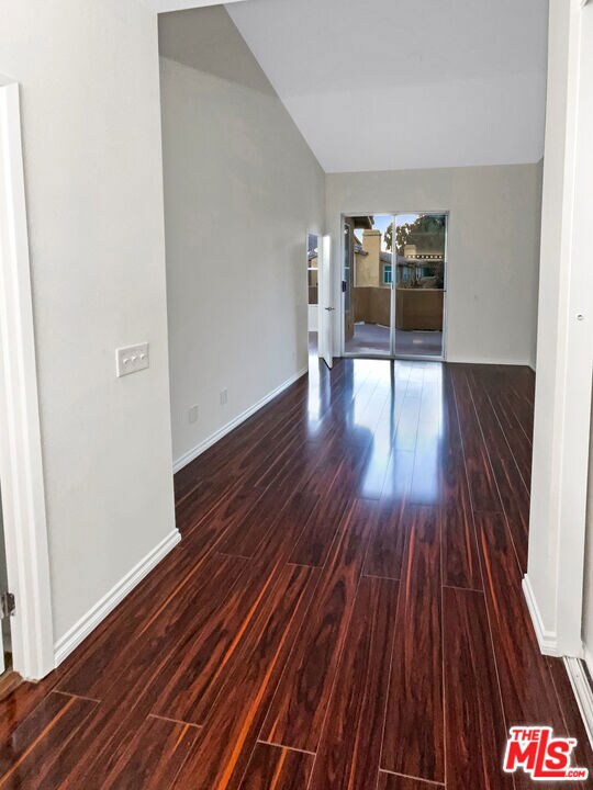 unfurnished room featuring lofted ceiling and dark wood-type flooring