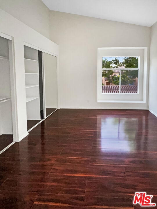 unfurnished bedroom with vaulted ceiling and dark hardwood / wood-style floors