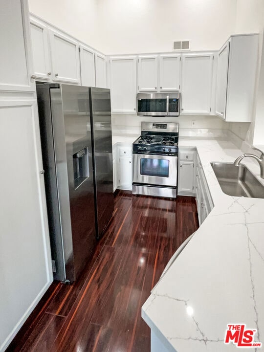 kitchen featuring light stone counters, appliances with stainless steel finishes, and dark hardwood / wood-style floors