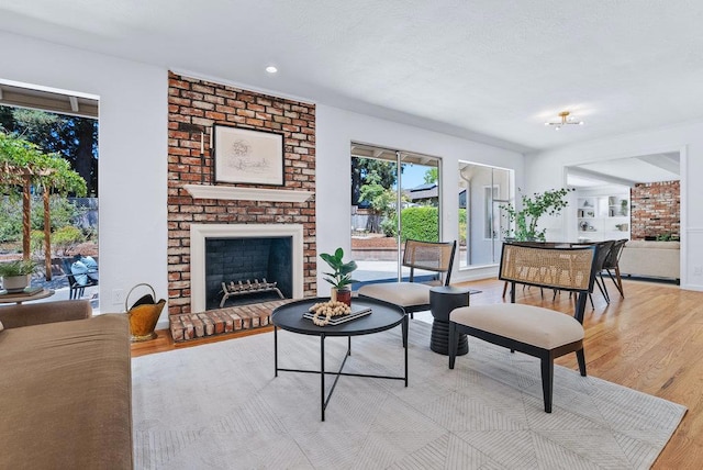 living room with a brick fireplace and light hardwood / wood-style floors