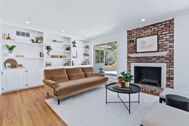 living room featuring a fireplace, light hardwood / wood-style floors, and built in shelves