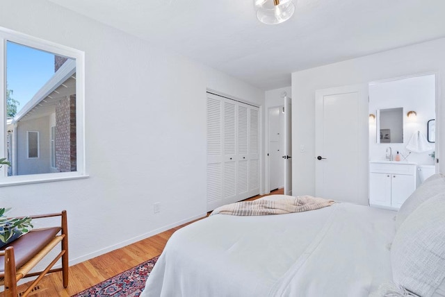 bedroom featuring a closet, connected bathroom, and light hardwood / wood-style flooring