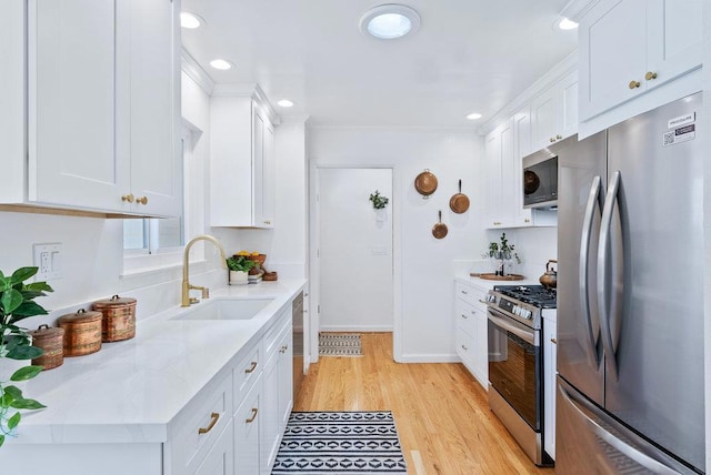 kitchen featuring stainless steel appliances, white cabinetry, sink, and light stone counters