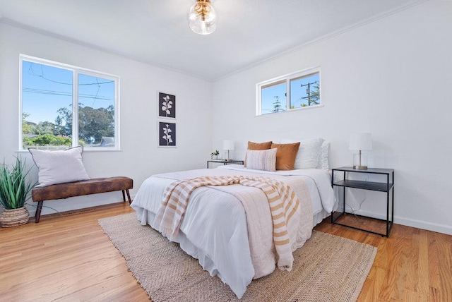 bedroom with multiple windows, crown molding, and light wood-type flooring