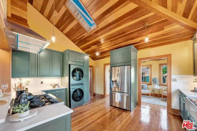 kitchen with appliances with stainless steel finishes, decorative light fixtures, stacked washer and dryer, backsplash, and green cabinets