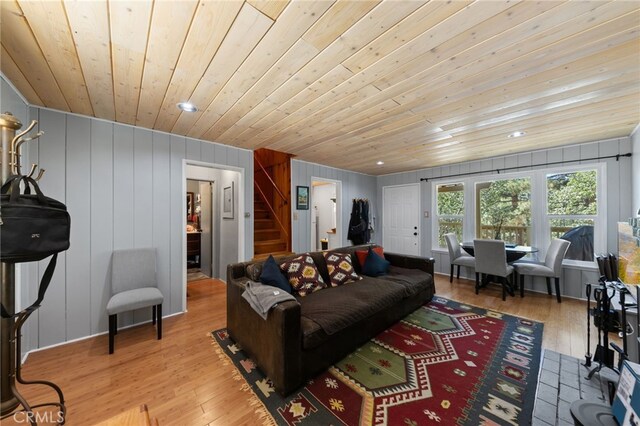 living room with light hardwood / wood-style flooring, wood ceiling, and wooden walls