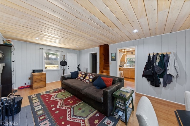 living room featuring light hardwood / wood-style flooring, wood ceiling, and wood walls