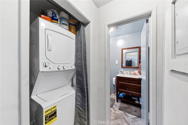 laundry room featuring stacked washer / drying machine and sink