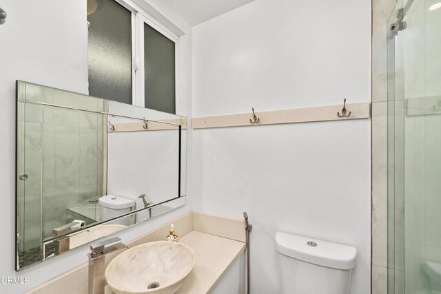 bathroom featuring vanity, a shower with shower door, and toilet