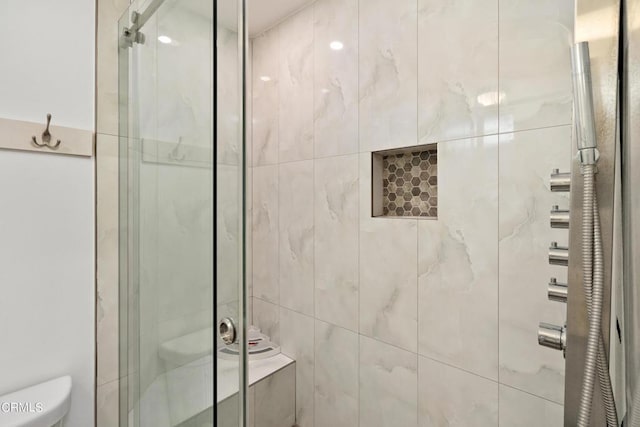 bathroom featuring toilet and a shower with shower door