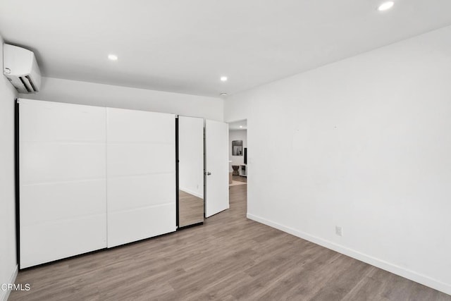 unfurnished bedroom featuring a wall unit AC and light hardwood / wood-style flooring