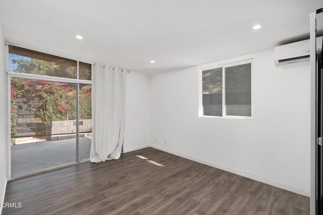 spare room featuring a healthy amount of sunlight, a wall mounted AC, and dark hardwood / wood-style flooring