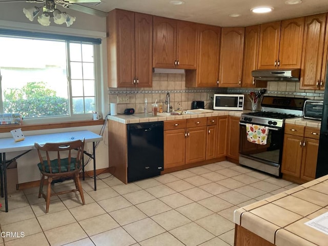 kitchen with tile countertops, dishwasher, range, and light tile patterned floors