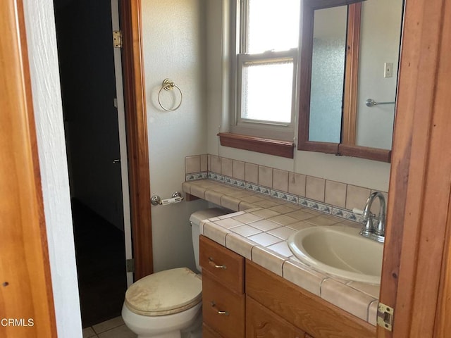 bathroom with tile patterned flooring, vanity, tasteful backsplash, and toilet