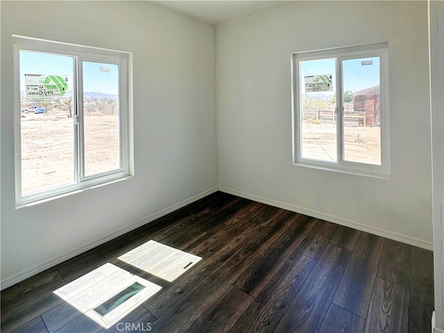 unfurnished room featuring dark wood-style floors, visible vents, and baseboards