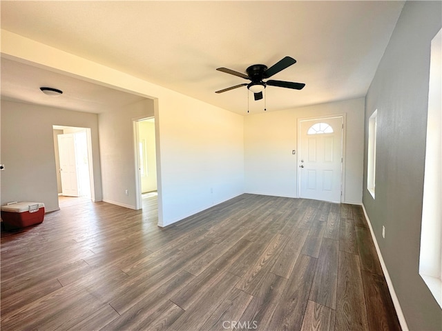 empty room with ceiling fan, dark wood-type flooring, and baseboards