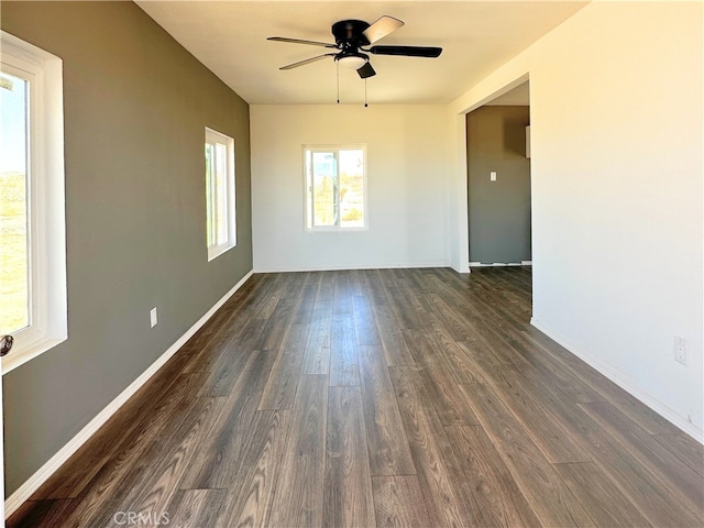 empty room featuring dark wood-style flooring, ceiling fan, and baseboards