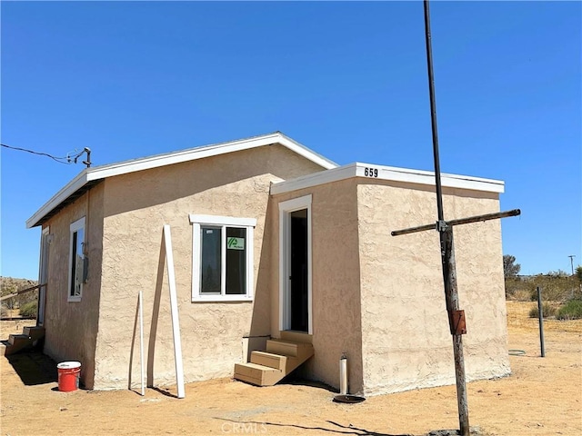 back of property with entry steps and stucco siding