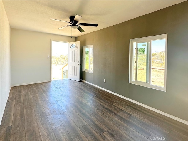 empty room featuring ceiling fan, baseboards, and dark wood-type flooring