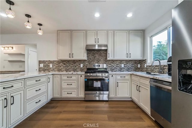 kitchen with pendant lighting, backsplash, dark wood-type flooring, appliances with stainless steel finishes, and light stone counters