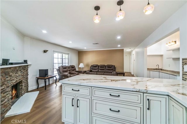 kitchen with a fireplace, light stone countertops, dark hardwood / wood-style flooring, and hanging light fixtures