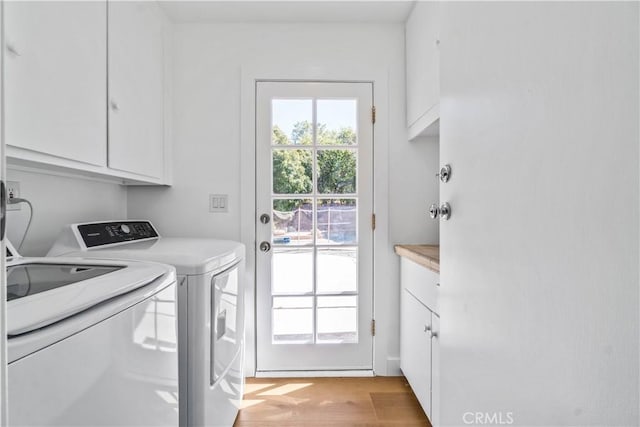 laundry room featuring washer and dryer, cabinets, and light wood-type flooring