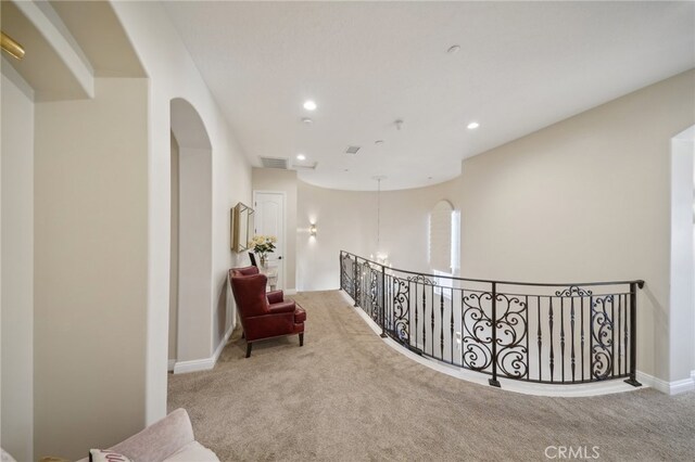 hallway featuring a chandelier and light colored carpet