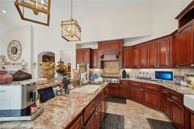 kitchen with a chandelier, a high ceiling, pendant lighting, stainless steel gas cooktop, and sink