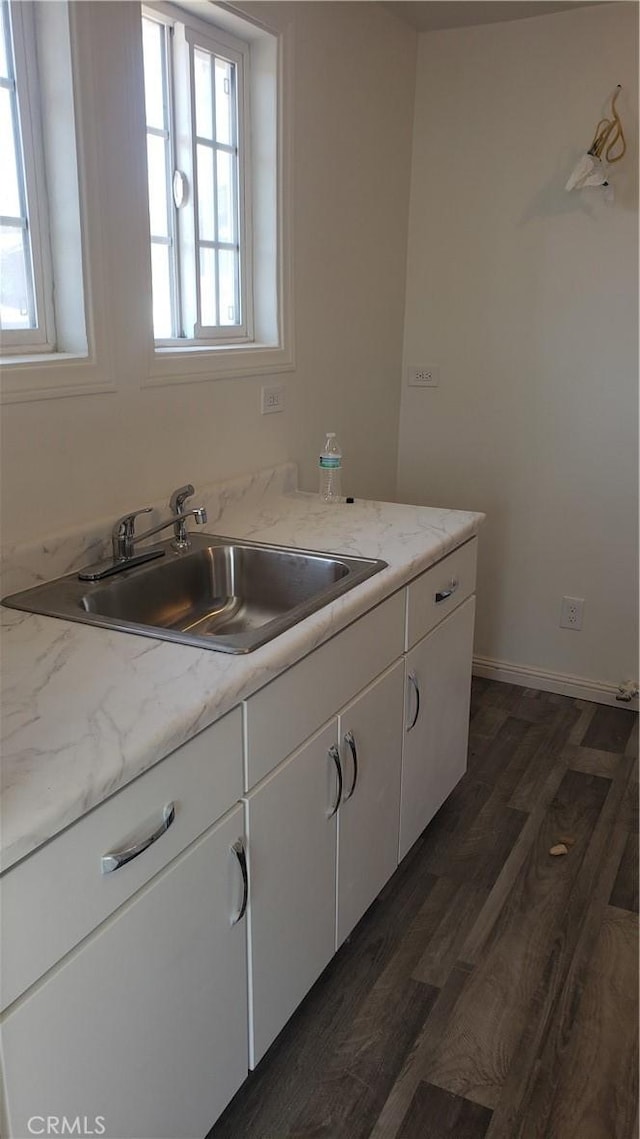 kitchen featuring white cabinetry, light stone countertops, sink, and dark wood-type flooring