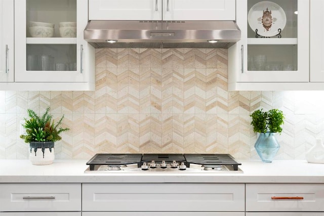 kitchen with stainless steel gas stovetop, decorative backsplash, and white cabinetry