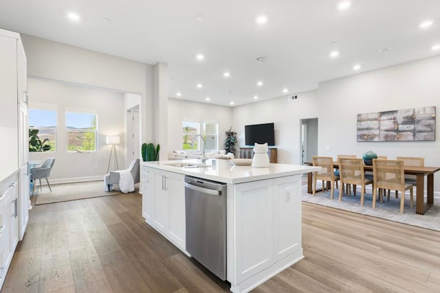 kitchen with a wealth of natural light, sink, white cabinets, a center island with sink, and stainless steel dishwasher