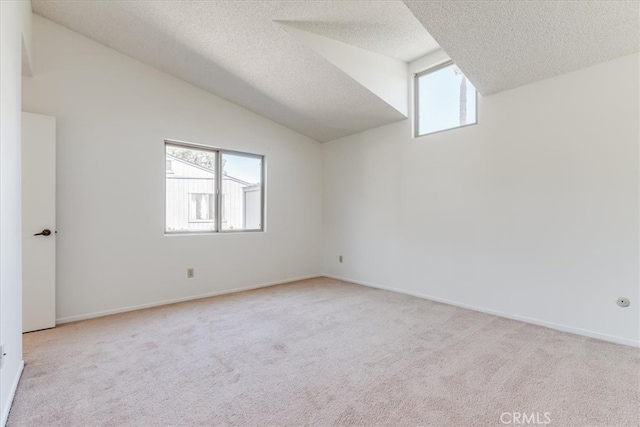 carpeted spare room featuring a textured ceiling and lofted ceiling