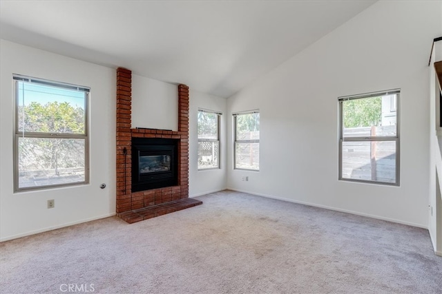 unfurnished living room with light carpet, a fireplace, vaulted ceiling, and a healthy amount of sunlight