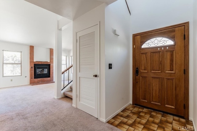 foyer featuring dark colored carpet, a brick fireplace, and plenty of natural light