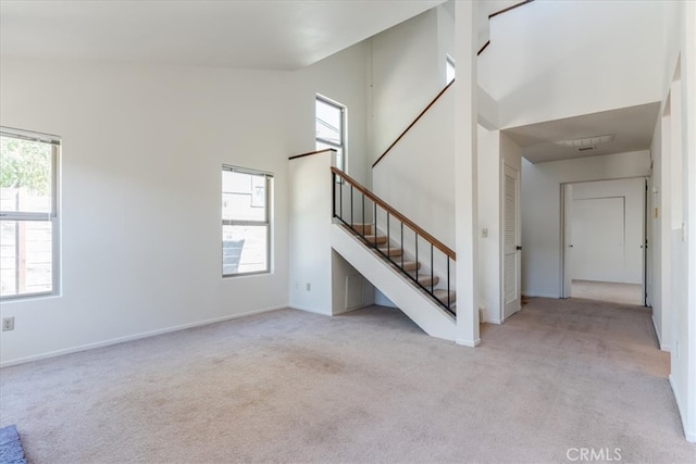 unfurnished living room with light carpet and a towering ceiling