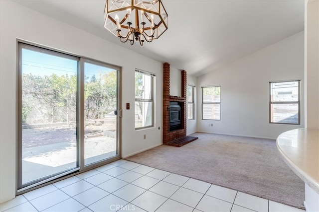 unfurnished living room with a notable chandelier, a brick fireplace, vaulted ceiling, and light colored carpet