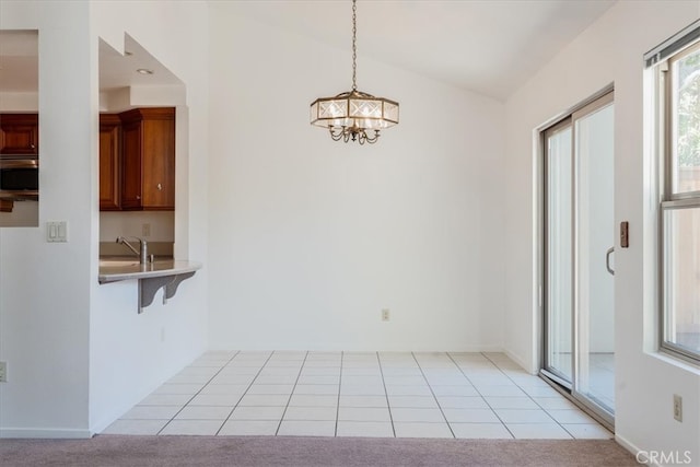 unfurnished dining area with vaulted ceiling, sink, light carpet, and a chandelier