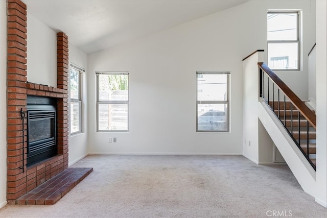 unfurnished living room featuring high vaulted ceiling, light carpet, and a brick fireplace