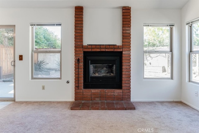 unfurnished living room featuring carpet floors, a healthy amount of sunlight, and a brick fireplace