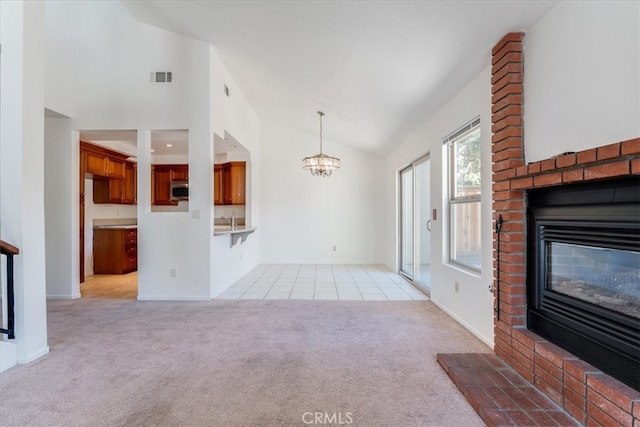 unfurnished living room with a fireplace, vaulted ceiling, light colored carpet, and a notable chandelier