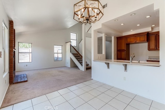 kitchen with lofted ceiling, kitchen peninsula, a kitchen bar, hanging light fixtures, and light carpet