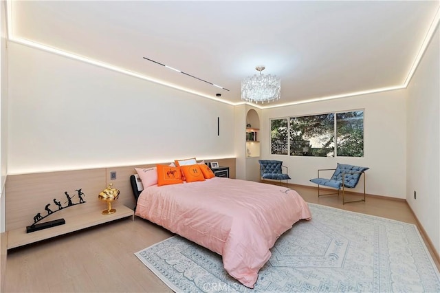 bedroom with a chandelier, track lighting, and hardwood / wood-style flooring