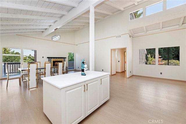 kitchen featuring a fireplace, light hardwood / wood-style flooring, white cabinetry, and a healthy amount of sunlight