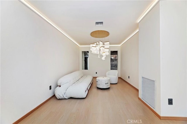 living area featuring hardwood / wood-style flooring, a notable chandelier, and ornamental molding