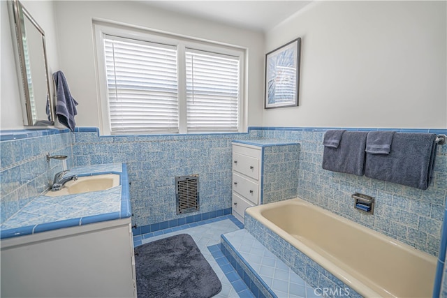 bathroom with vanity, tile walls, tile patterned flooring, and a washtub