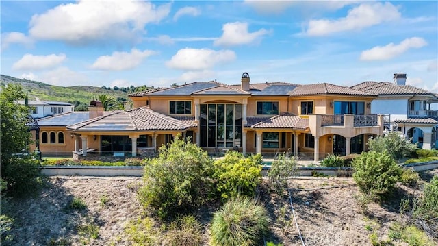 rear view of house with a mountain view and a balcony