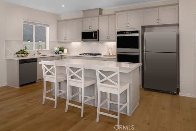 kitchen featuring sink, stainless steel appliances, light hardwood / wood-style floors, and a kitchen breakfast bar